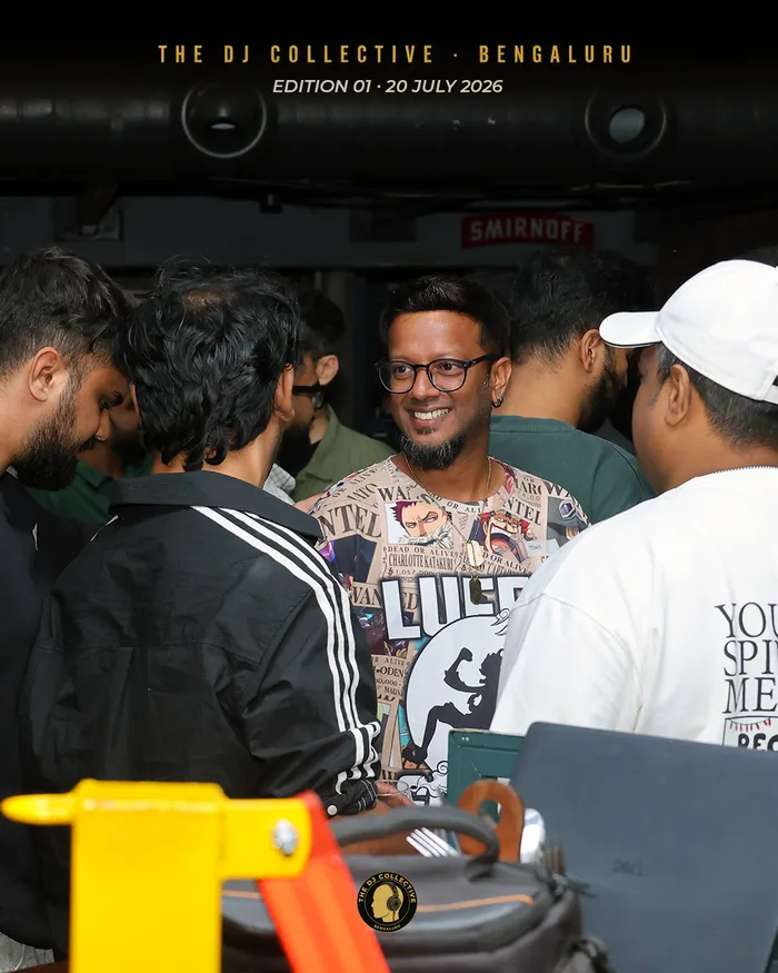 A DJ smiling in a packed crowd near the bar