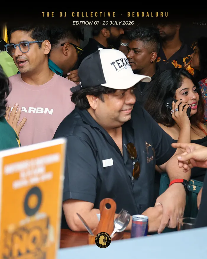 A table of DJs mid-conversation, one leaning in to hear over the noise