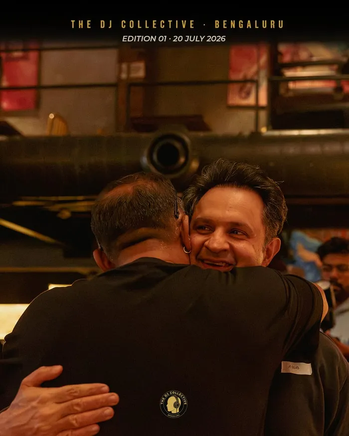 Two DJs in a hug, one smiling over the shoulder